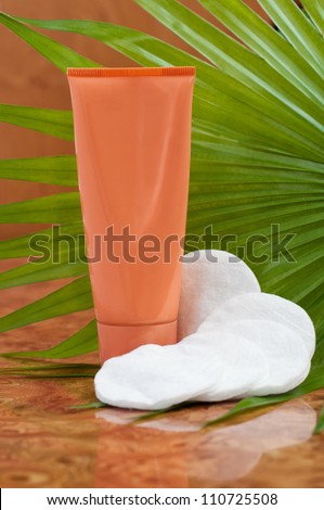 Orange cosmetic tube and cosmetic sponges  on palm leaf