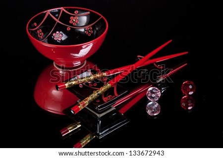 Chinese sticks and red dish on a black background