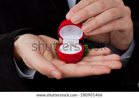 Engagement ring in hands. Man in suit holding an open box with engagement ring inside
