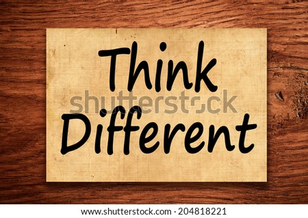 Think different concept written on grunge paper on wooden background