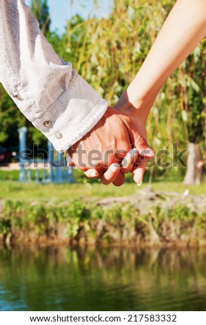 Beautiful image of a young couple in love holding hands in the park near the lake