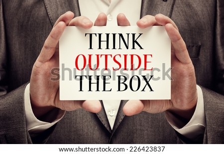 Think outside the box. Businessman holding a signboard with a message text written on it