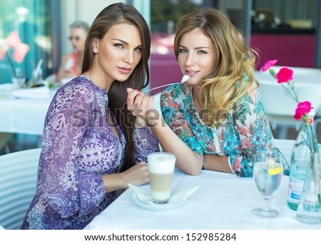 Two beautiful women in restaurant drinking coffee and water