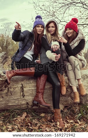 Happy tree girls wearing a woolly hats and showing something