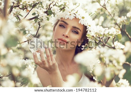 Woman with bottle of perfume in the garden