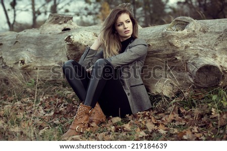 Young girl sitting outdoor in autumn scenery