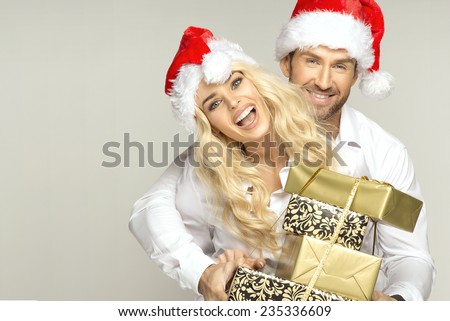 Portrait of cheerful couple in santa claus hats with presents