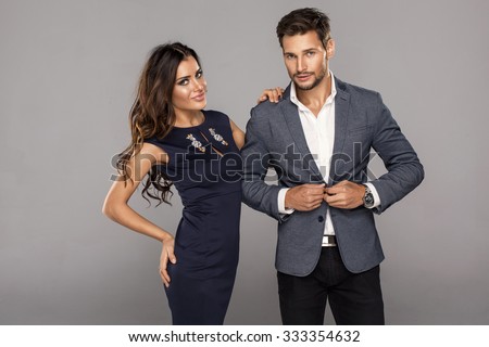 Portrait of young handsome man buttoning jacket with beautiful young woman. Beautiful couple in fashionable clothes