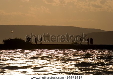 people walking in the sunset on the mole