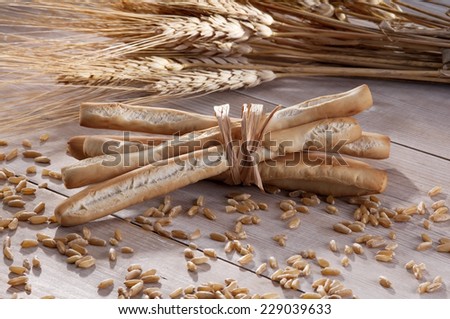 Group of bread sticks and ears of wheat, freshly baked on an old wooden table