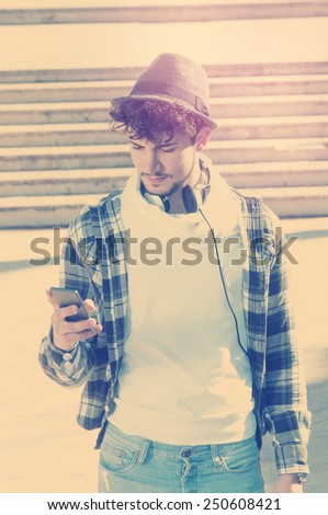 young hipster man watching smart phone in the street applied filter instagram style and a flare effect