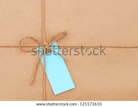 String tied in a bow with card over brown paper packaging.