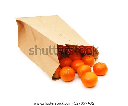 Mandarin orange fruit in a brown paper recycled carrier bag with leaf sprig isolated over white background.