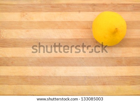 Yellow lemon  sit on a worn butcher block cutting board