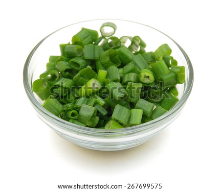 chopped green onions in glass bowl on white
