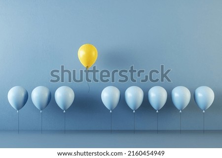 Independence, think different and uniqueness concept with yellow balloon standing out from crowd of blue balloons. 3D rendering