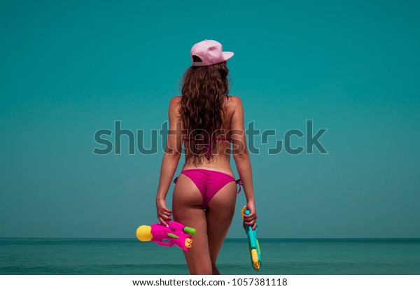 Back View Of Beautiful Girl In Pink Bikini And Cap Standing With Water