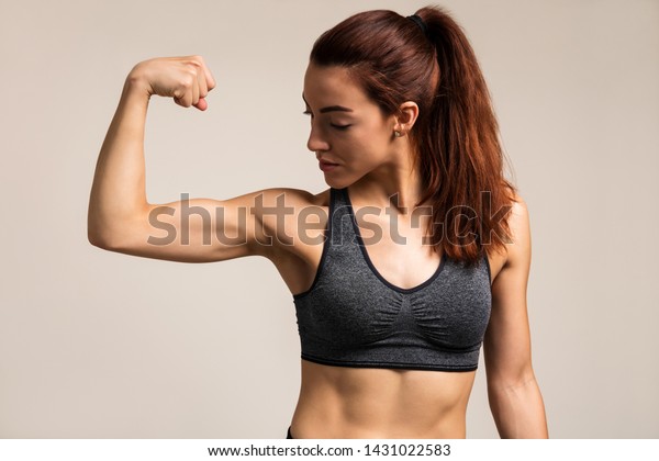 Beautiful Female Athlete Flexing Muscles While Stock Photo 1431022583