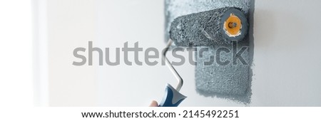 Closeup of renovation crew painting wall grey with painting roll