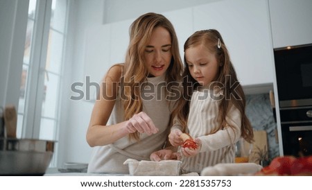 Curious daughter decorating cake with mom at kitchen closeup. Loving woman teach kid bake at home. Friendly family cooking dessert. Single mother and baby girl enjoying domestic routine together