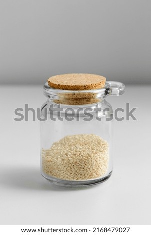 food storage, healthy eating and diet concept - jar with sesame seeds on white background