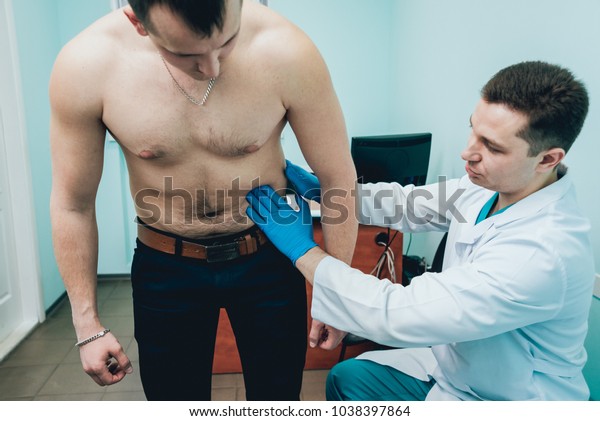 Врач пальпирует анал пациента гея