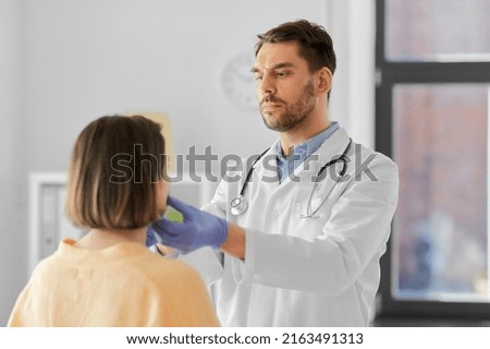 medicine, healthcare and people concept - male doctor checking lymph nodes of woman patient at hospital