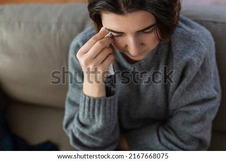 mental health, psychological problem and depression concept - sad crying woman with paper tissue sitting on sofa at home