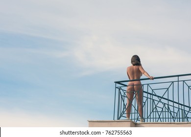 Naked Female Stands On Balcony Opposite Stock Photo