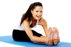 Athletic woman smiling while she stretches forward, Part of a collection of yoga poses by a fit active mixed race woman; sit-up pose.