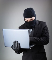 Computer Hacker in suit and tie stealing data from laptop computer, isolated on white