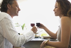 Mature couple toasting with red wine while having lunch in a hotel.