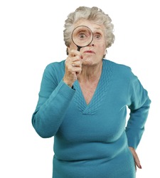 portrait of a senior woman looking through a magnifying glass over a white background