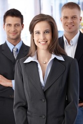Official business team portrait, confident, smiling businesspeople standing in office.