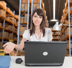 Female administrative in a desk with a distribution warehouse in the background
