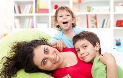 Happy mother and her children playing together at home - motherhood concept