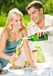 Young happy smiling cheerful attractive couple celebrating with champagne, outdoor