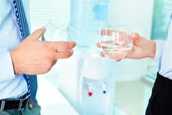Photo of business partners hands holding glasses with water