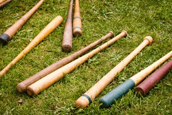 Several colorful old wooden vintage baseball bats are scattered on a green grass background