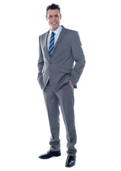 Handsome business executive posing with hands in pocket. Full length portrait