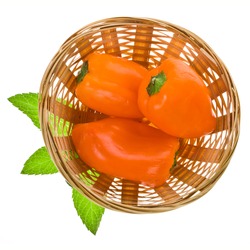 three sweet orange peppers in a wicker basket are a top view isolated on white background