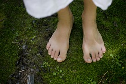 A young girl's bare feet feeling the softness of the green moss connecting with the earth
