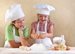 Kids preparing the dough for a cookie, pizza or pasta - having fun breaking the eggs