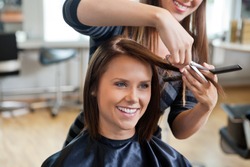 Happy young woman getting a new haircut by hairdresser at parlor