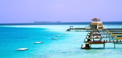 Landscape photo of Island in ocean, over water villa with endless swimming pools. Maldives.