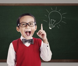 Portrait of male elementary school student with lightbulb picture on blackboard