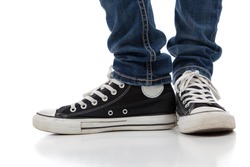 A pair of vintage looking, athletic shoes and skinny jeans on a white background with copy space