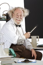 Cheerful eccentric senior scientist in his lab points to blackboard and explains his ideas. High key, vertical, copy space.