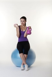Beautiful Young Woman choosing if she should work out on her gym ball and weights or eat a nice unhealthy cake