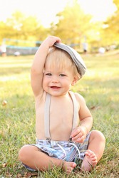 Baby, toddler boy wearing suspenders and a country / newsboy hat, outdoors, featuring seasonal, fall colors, suitable for Thanksgiving or Halloween or Fall theme